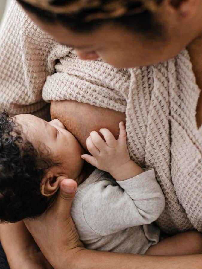 New mom in beige sweater breastfeeding baby