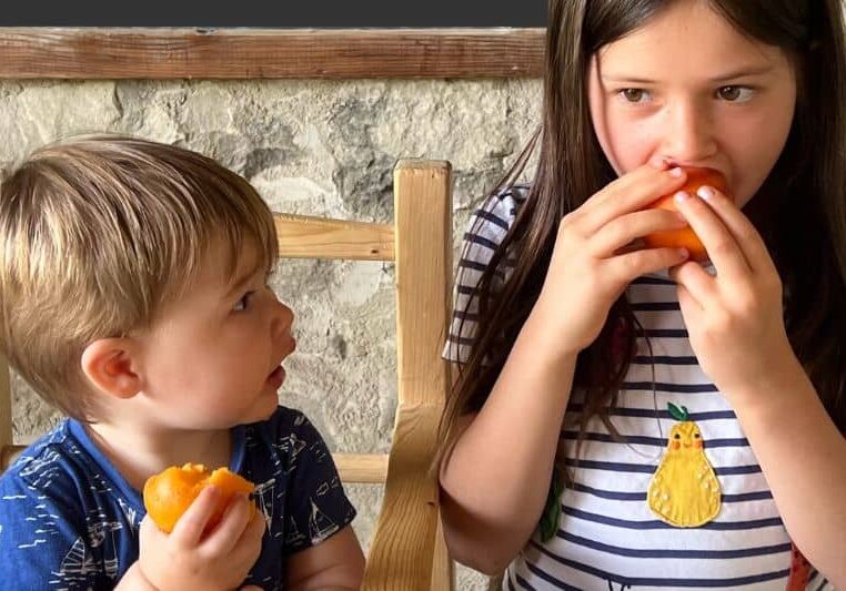 baby and young girl eating fruit